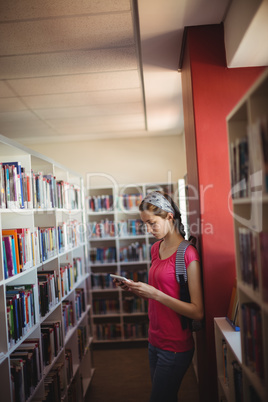 Attentive schoolgirl using digital tablet in library