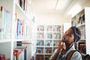 Schoolgirl selecting book from book shelf in library