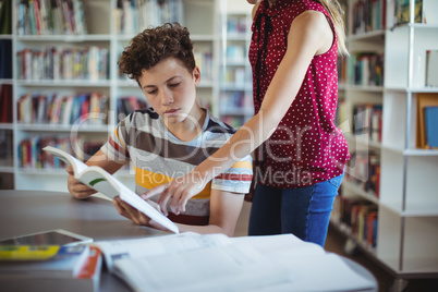 Classmates reading book in library