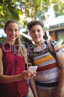 Portrait of happy classmates using mobile phone