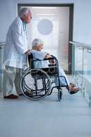 Doctor and senior patient on wheelchair in the passageway