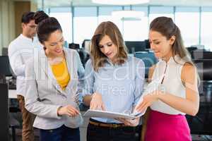 Business colleagues discussing over clipboard at desk in office