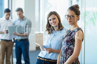 Smiling business colleagues using digital tablet in office