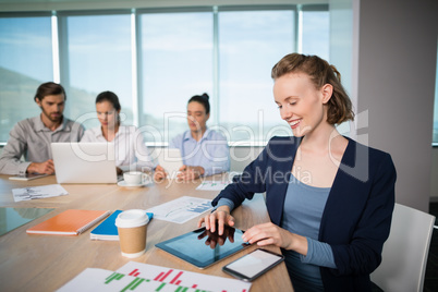 Smiling female business executive using digital tablet in conference room