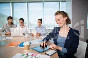 Smiling female business executive using digital tablet in conference room