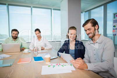 Business executives discussing over digital tablet in conference room
