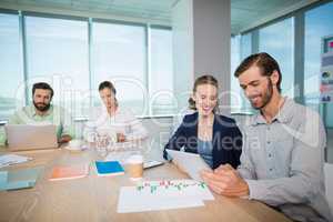 Business executives discussing over digital tablet in conference room
