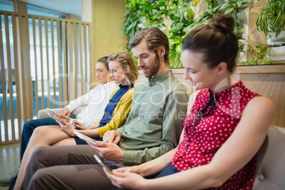 Business executives using electronic devices while sitting