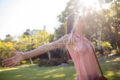 Carefree woman standing with her arms spread in the park