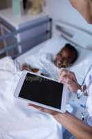 Female doctor using digital tablet during visit in ward