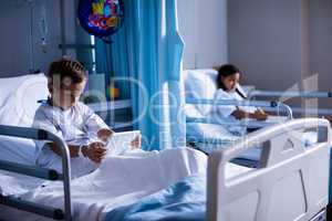 Patients with digital tablet and book sitting on bed
