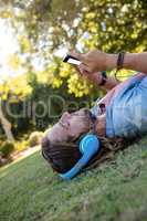 Man listening to music and using mobile phone while lying on grass