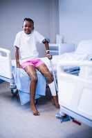 Girl with crutches sitting on hospital bed in ward