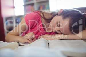 Tired schoolgirl sleeping while studying in library