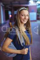 Happy schoolgirl standing with schoolbag in school campus