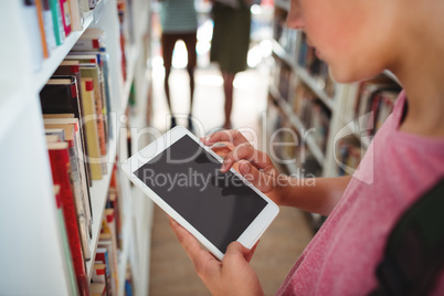 Schoolboy using digital tablet in library