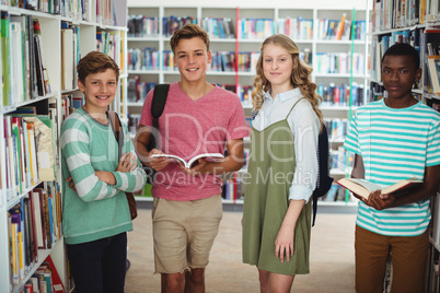 Portrait of happy classmates standing in library