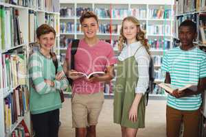 Portrait of happy classmates standing in library