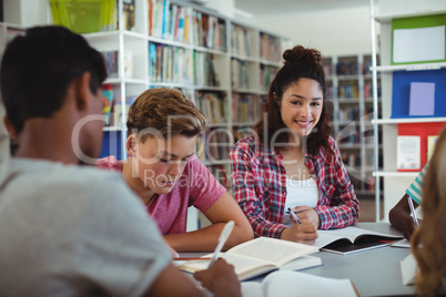 Portrait of happy schoolgirl studying with his classmates in library