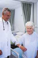 Doctor assisting senior patient in ward