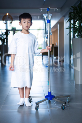 Boy patient holding intravenous iv drip stand in corridor