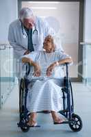 Doctor holding senior patient on wheelchair in passageway