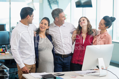 Smiling business colleagues interacting with each other at desk