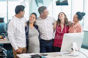 Smiling business colleagues interacting with each other at desk