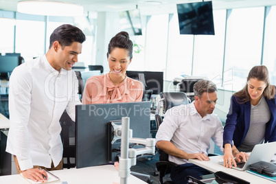 Business colleagues interacting with each other at desk in office