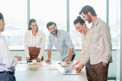 Smiling business executives discussing with each other in conference room