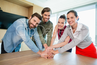 Business executives with their hands stacked on wooden table at office