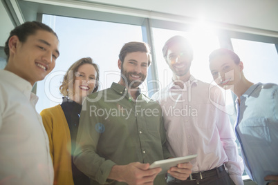 Smiling business executives with digital tablet standing in office