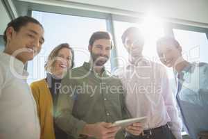 Smiling business executives with digital tablet standing in office