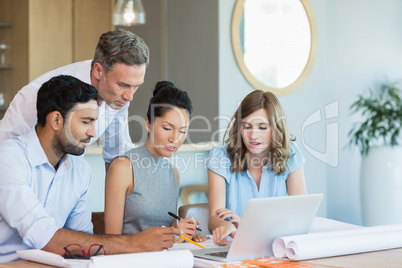 Architects discussing over laptop in conference room