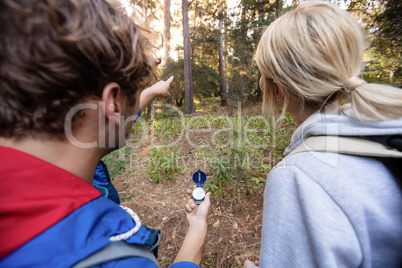 Rear view of hiking couple holding a compass and pointing forward