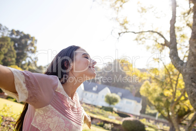 Woman standing with arms outstretched in park