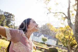 Woman standing with arms outstretched in park