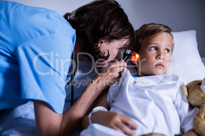 Female doctor examining patient ear with otoscope