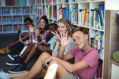Students sitting in library and waving hands