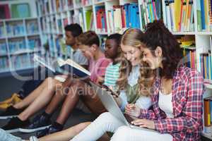 Students using mobile phone and laptop in library