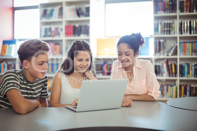 Happy students using laptop in library