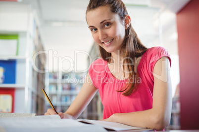 Schoolgirl doing homework in in library at school