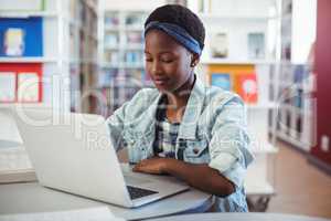 Schoolgirl using laptop in library
