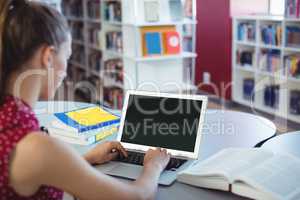 Schoolgirl using laptop in library