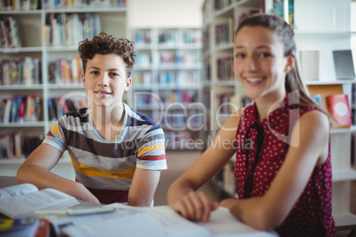 Portrait of happy schoolboy sitting with his classmate in library