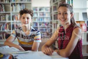 Portrait of happy schoolboy sitting with his classmate in library