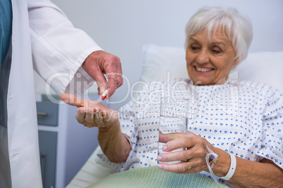 Doctor giving medicine pill to senior patient