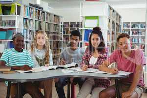 Portrait of happy classmates studying in library