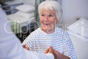 Doctor consoling senior patient in ward