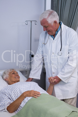 Doctor consoling senior patient in ward